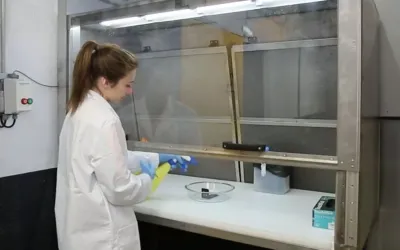 Opératrice devant une sorbonne pour initier les essais de tenue aux fluides